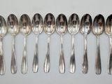 six silver spoons are lined up in a row on a white surface