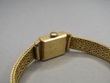 a close up of a gold wrist watch with a chain around it