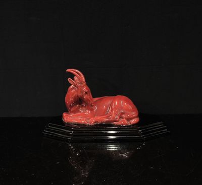 statue d'une chèvre rouge sur un socle noir
