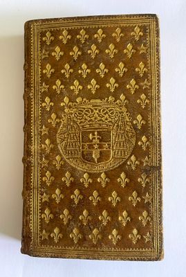 an old book with a gold cover sitting on a white surface