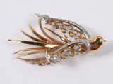 a gold and diamond brooch with a bird on it