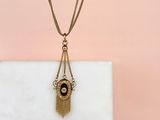 a gold and black necklace with a tassel hanging from it