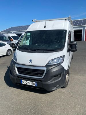 La camionnette blanche est garée sur un parking, à côté d'autres voitures.