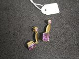 pair of earrings with amethorate and pink stones on a black surface