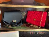 two purses sitting on a shelf next to each other