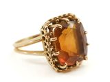 un gros plan d'une bague en or sertie d'une grosse pierre brune