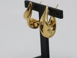 a close up of a pair of gold earrings on a black stand