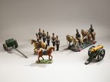 plusieurs figurines de soldats et un canon posés sur une surface blanche