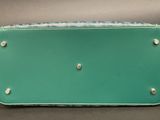 a green purse sitting on top of a table next to a black table