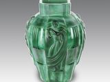 a green vase with a statue of a woman on it