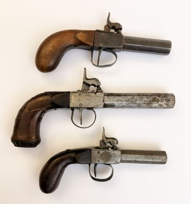 trois vieux revolvers sont alignés sur une surface blanche