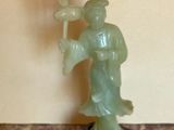 une statue représentant un homme tenant une fleur, posée sur une table
