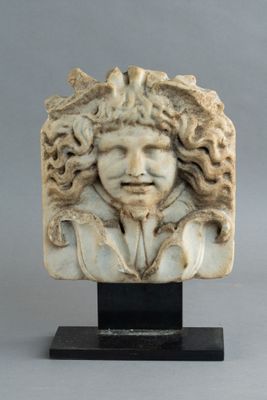 tête sculptée d'un homme aux cheveux bouclés, posée sur un socle noir