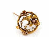 a close up of a gold broochle with flowers on it