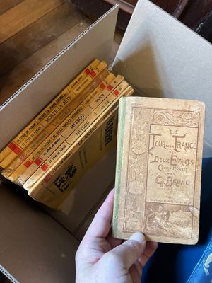 une personne tenant un livre devant une boîte remplie de livres
