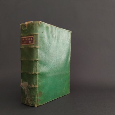 an old green book sitting on top of a black table