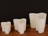 trois vases blancs posés les uns à côté des autres sur une table en bois