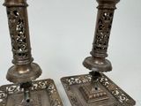 two metal candlesticks that are on a table
