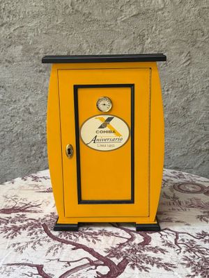 une petite armoire jaune surmontée d'une horloge