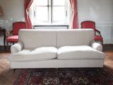 une photo d'un salon avec un canapé blanc et des fauteuils rouges