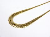 gros plan d'un collier en or sur une surface blanche