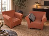 deux fauteuils orange dans un salon, avec une plante dans un coin