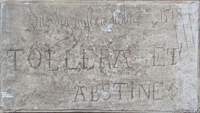 une plaque en pierre fixée sur le mur d'un immeuble et sur laquelle figurent des inscriptions