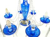 un lustre en verre bleu surmonté d'un vase bleu