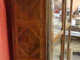 a wooden cabinet with a glass door and a red curtain behind it