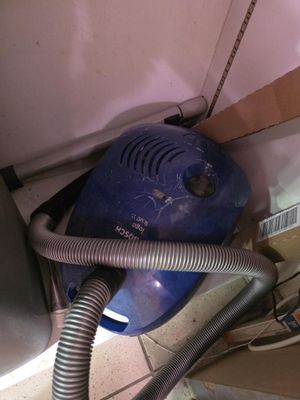 un sèche-cheveux bleu posé par terre à côté d'une pile de cartons