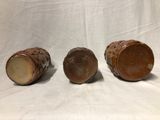 three pieces of pottery sitting on top of a white cloth