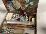 une personne tenant un pinceau et une palette dans une boîte en bois