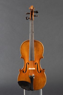 an old violin sitting on a stand against a gray background