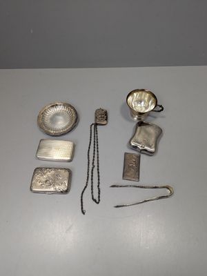 Plusieurs objets en argent sont disposés sur une surface blanche