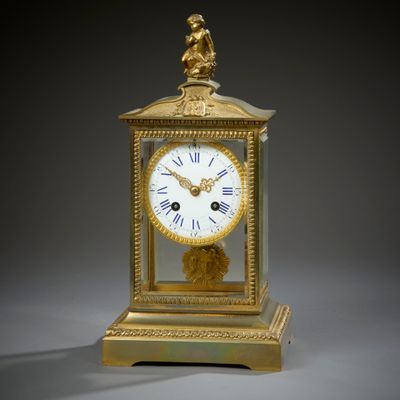 Pendule cage en bronze ciselé et doré sommée d'un amour, le …