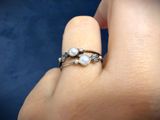 someone is holding a ring with pearls and diamonds on it