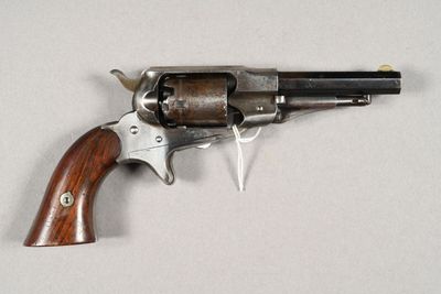 un vieux revolver avec une poignée en bois sur une surface blanche
