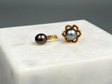 paire de boucles d'oreilles à clous en forme de fleur, en perles et or, posées sur un bloc de marbre
