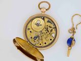 a gold pocket watch with a blue bead hanging from it