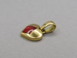a close up of a gold heart shaped pendant with a red stone