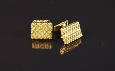 une paire de boutons de manchette en or posés sur un fond noir