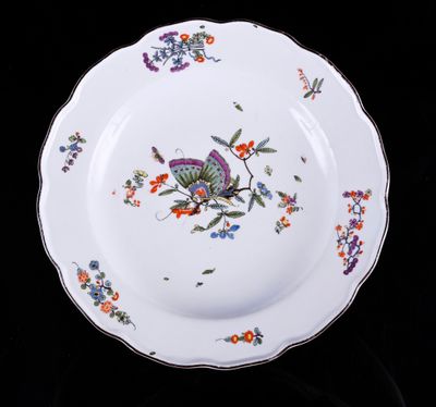 une assiette sur laquelle est représenté un papillon sur fond noir