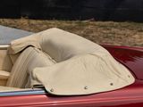 a red convertible car with a tan cloth on the top