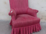 a red chair with a ruffled skirt on the floor