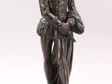 an antique bronze statue of a man with a hat and a cane