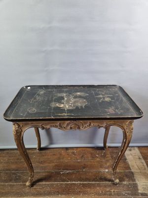 an old table with a black top sitting on top of a wooden floor