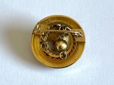 a gold brooch with a skull on it on a white surface