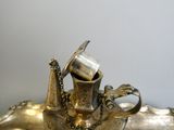 a silver plate with a silver teapot on top of it