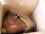 une valise marron dans un carton sur lequel est accrochée une étiquette
