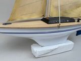 a model of a sailboat on a stand on a white surface